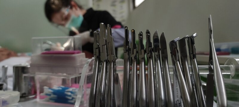 Horizontal photo in color of orthodontic tools and a orthodontist in the background, in a dental clinic, making procedure and health care