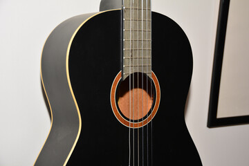 Fototapeta premium A black acoustic guitar on a wall in a home music studio