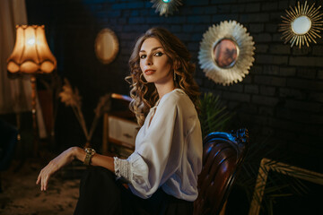 Young beautiful woman wearing elegant vintage outfit, posing in dark interior. Copy, empty space...
