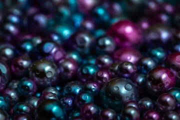 Fototapeta na wymiar Beautiful background with nacreous dark pearls, top view. Abstract texture for festive backgrounds. Shiny multicolored dark surface of Christmas decorations. Gems close-up. Black bright background.