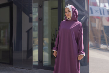 Islamic beautiful woman in a Muslim dress standing on a summer park street background forest autumn...