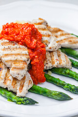 grilled poultry meat with baked red pepper sauce and green asparagus