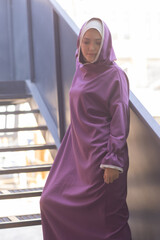 Islamic beautiful woman in a Muslim dress standing on a summer park street background forest autumn...
