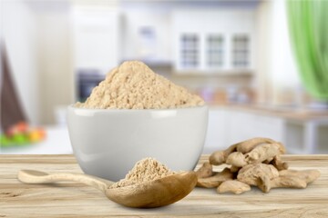 Turmeric powder in the bowl and root on the desk