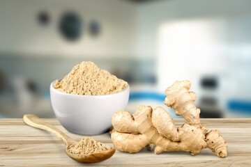 Turmeric powder in the bowl and root on the desk