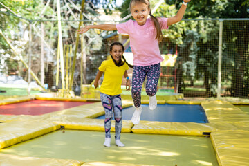 two young active girls doing exercises for squatting with trampoline