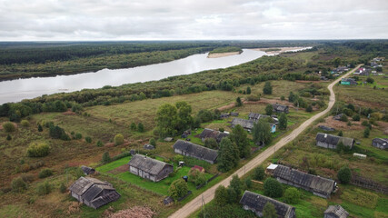 Beautiful aerial panorama of a Russian village near a wide river. Autumn rural landscape.