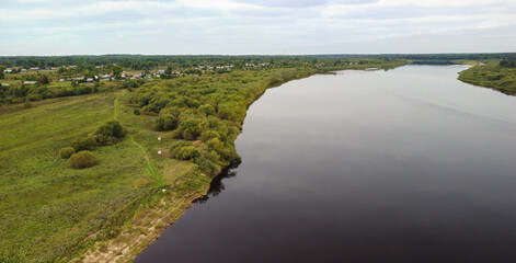 Naklejka premium Beautiful aerial panorama of a Russian village near a wide river. Autumn rural landscape.