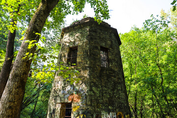 a stone cylinder shaped building in the forest covered with colorful graffiti surrounded by lush green trees and plants at Lullwater Preserve in Decatur Georgia USA