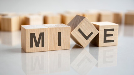word MILE on wooden cubes, gray background