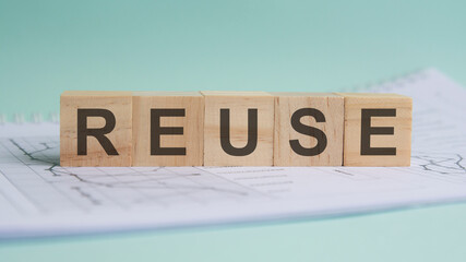 reuse is written on light wooden blocks. the word is located on a sheet with charts and graphs