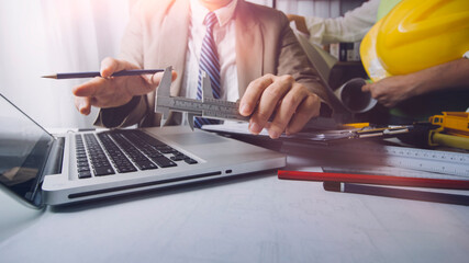Two colleagues discussing data working and tablet, laptop with on on architectural project at construction site at desk in office
