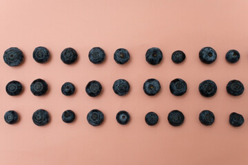 Top view of blueberries arranged in rows on an old pink background