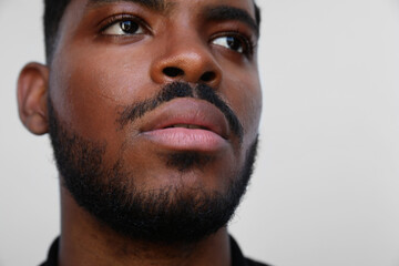 Obraz premium Cropped portrait of handsome muscular black man looking a side on white wall.
