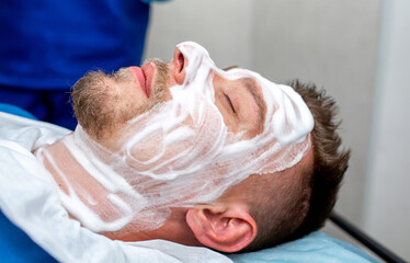 A man at a beautician's appointment. Treatments for men, face cleansing, skin peeling, moisturizing nourishing facial mask. Male spa salon.