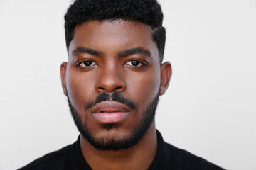 Portrait of handsome young black man looking straight over white background.