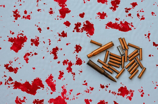 Many bullet casings (shells) of various calibers and one cartridge of caliber 7.62 mm against silver-white background with splashed red blood stains, anti-war and anti-terrorist themes