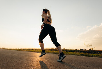 Young sporty girl running on a  road at sunset.   Lifestyle sports motivation. 