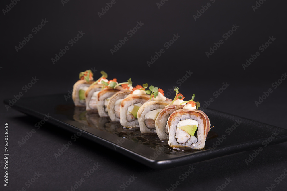 Sticker closeup of canada sushi rolls served on a black plate on a black background