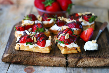 French waffles with strawberries and chocolate, cream cheese and nuts.