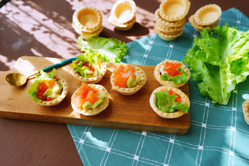 canape with salmon. Red fish in tarts on christmas lights background 