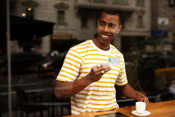 Handsome young african man in cafe drinking coffee. Portrait of happy man with credit card drinking coffee in cafe..