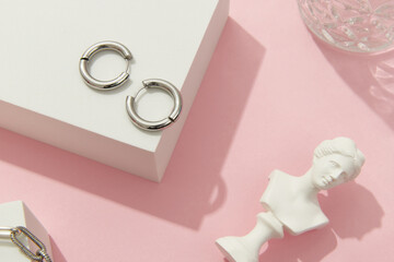 Creative composition with silver jewelry set on pink background. Trendy accessories in minimalist style