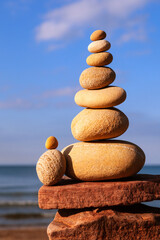 Rock zen pyramid of yellow stones on a beach on the background of the sea. Concept of Life balance