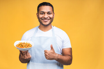 Portrait of of happy african american indian black man chef cooking pasta. Cooking, profession, haute cuisine, food and people concept isolated over yellow background.