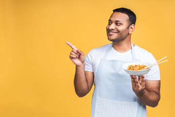 Portrait of of happy african american indian black man chef cooking pasta. Cooking, profession, haute cuisine, food and people concept isolated over yellow background.