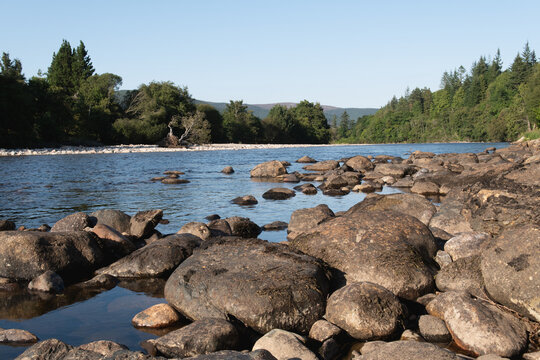Shore of River Dee on the outskrits of Ballater in Aberdeenshire in Scotland. It is an important area for wildlife. Forest in the background.