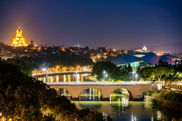 Fototapeta na wymiar Scenic view of Mtkvari river and Holy Trinity Cathedral at night