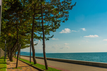 Fototapeta na wymiar KOBULETI, GEORGIA: Landscape with a view of the promenade by the beach on the Black Sea on a sunny summer day.