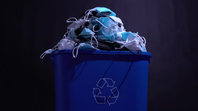 Medical masks in the recycle bin. Reusing and recycling of used personal protective equipment concept. Pollution by surgical masks in coronavirus pandemic. Covid-19 waste garbage, disposable masks.