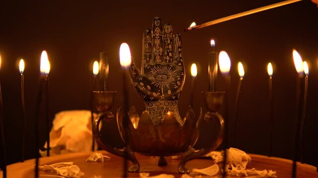 Palmistry and table statue of the black hand at fortune teller table. Mystic palm reading and magical black candles on candle holder. Occult knowledge and occultism. Spiritual mood.