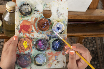 closeup to a paint stain, artist mixing colors on a palette with a brush, work tools, hobbie, creative lifestyle in studio, water paint texture