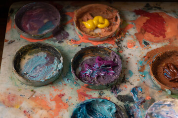 approach to a palette with circles, on top of water paint in different colors, object and tool for painting, hobby and wallpaper details in studio
