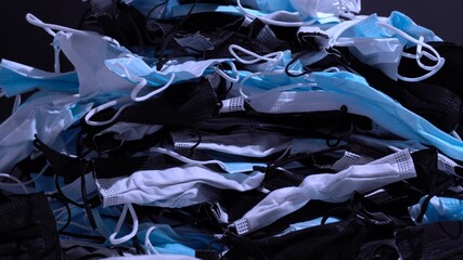 Medical masks on the table. Pile of used personal protective equipment PPE. Pollution by surgical masks during the coronavirus pandemic. A lot of Covid-19 plastic waste and garbage, disposable masks.