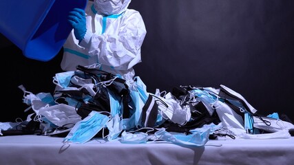 Recycle worker in gloves, sorting medical masks in the recycle bin. Depiction of recycle plant...