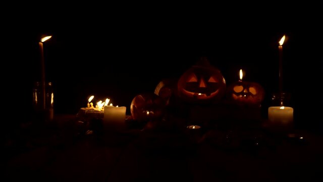 Three Jack pumpkins in candlelight on a dark background, loop video. Theme of autumn holidays, mystical rituals and traditions on Halloween. Craft handmade pumpkin for decoration. Video can be looped.