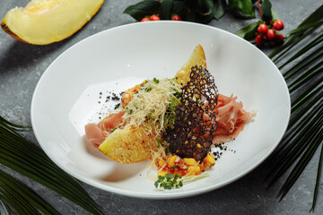 baked melon with parmesan and jamon on a white plate