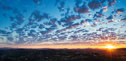 Beautiful sunset with popcorn clouds in San Diego East County with mountain views.