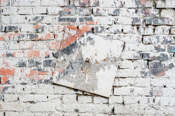 Old dirty brick wall with metal plate. Colorful grunge texture, peeling plaster. Abstract vintage background