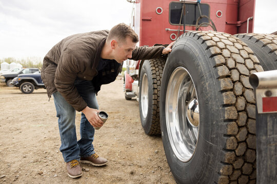 Male farmer inspecting semi truck tires