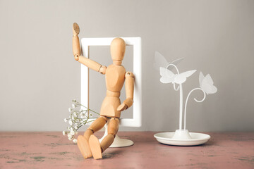 Wooden mannequin with flowers on light background