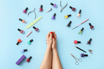 Female hands with tools for manicure and nail polishes on color background