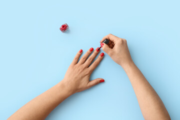 Woman doing manicure on blue background