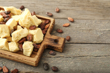 Board with cocoa butter and beans on wooden background