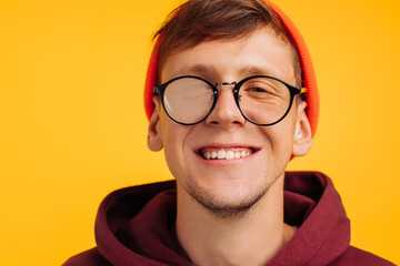 man has poor eyesight, a handsome guy in an orange hat and red light and glasses for sight, a fuzzy glass on his glasses