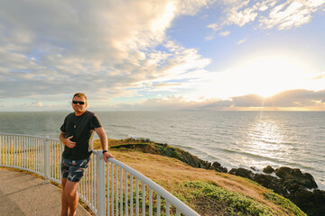 Man enjoying sunrise view from Lambert's Beach lookout in Mackay, Queensland Australia - obrazy, fototapety, plakaty